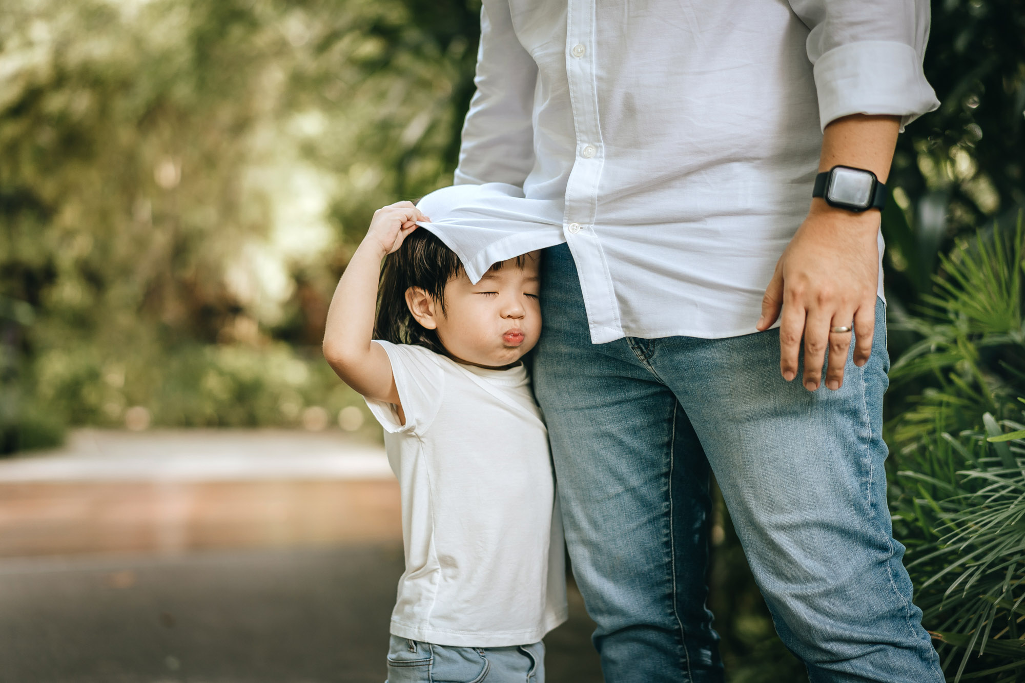 Son tries to hide under his father's shirt.