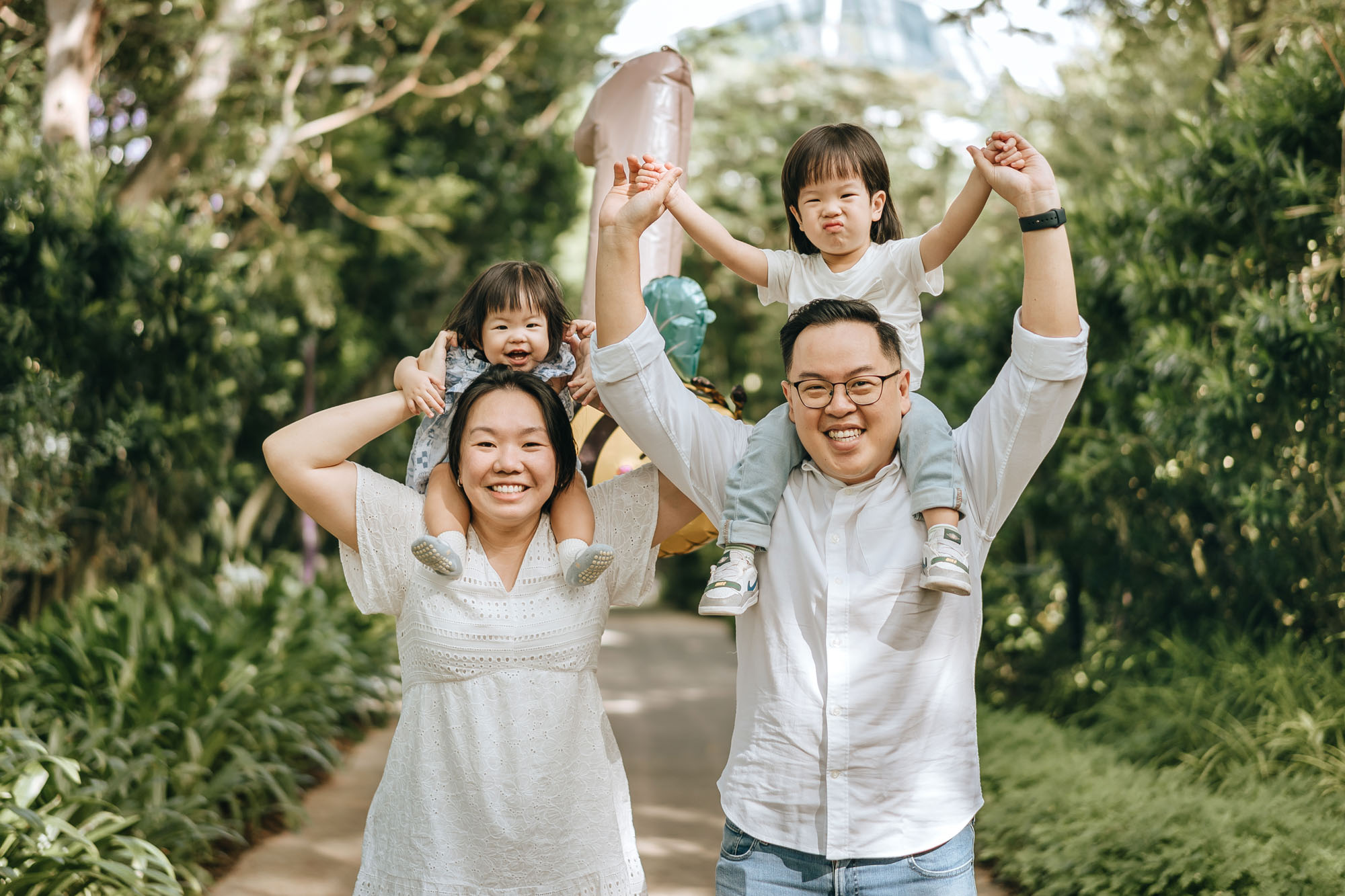 Kids making faces for the camera as they sit on the shoulders of their parents.