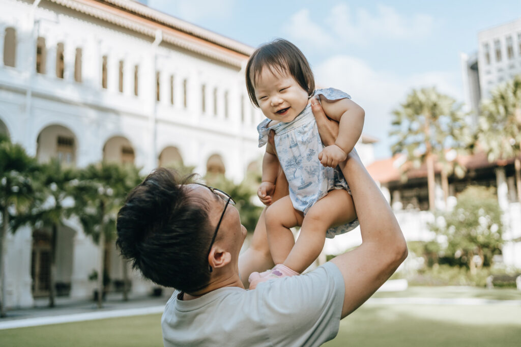 Proud father hold his baby high during a family photo shoot at the Raffles Hotel.
