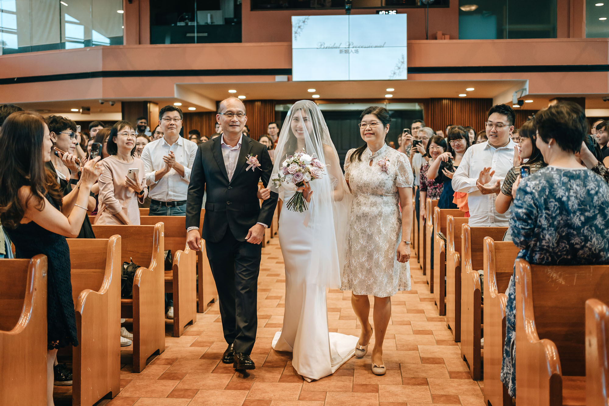 the bride and her parents walking down the aisle