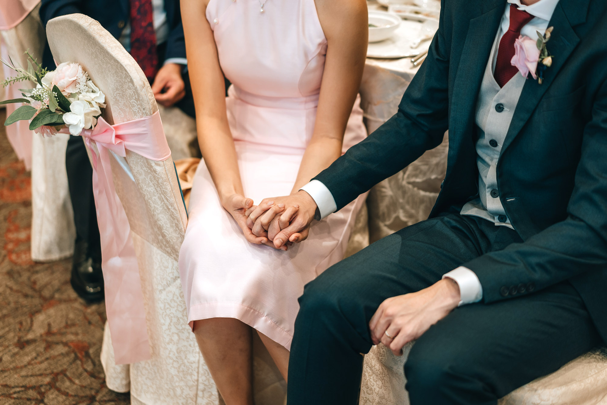bride and groom holding hands as they listen to the speeches