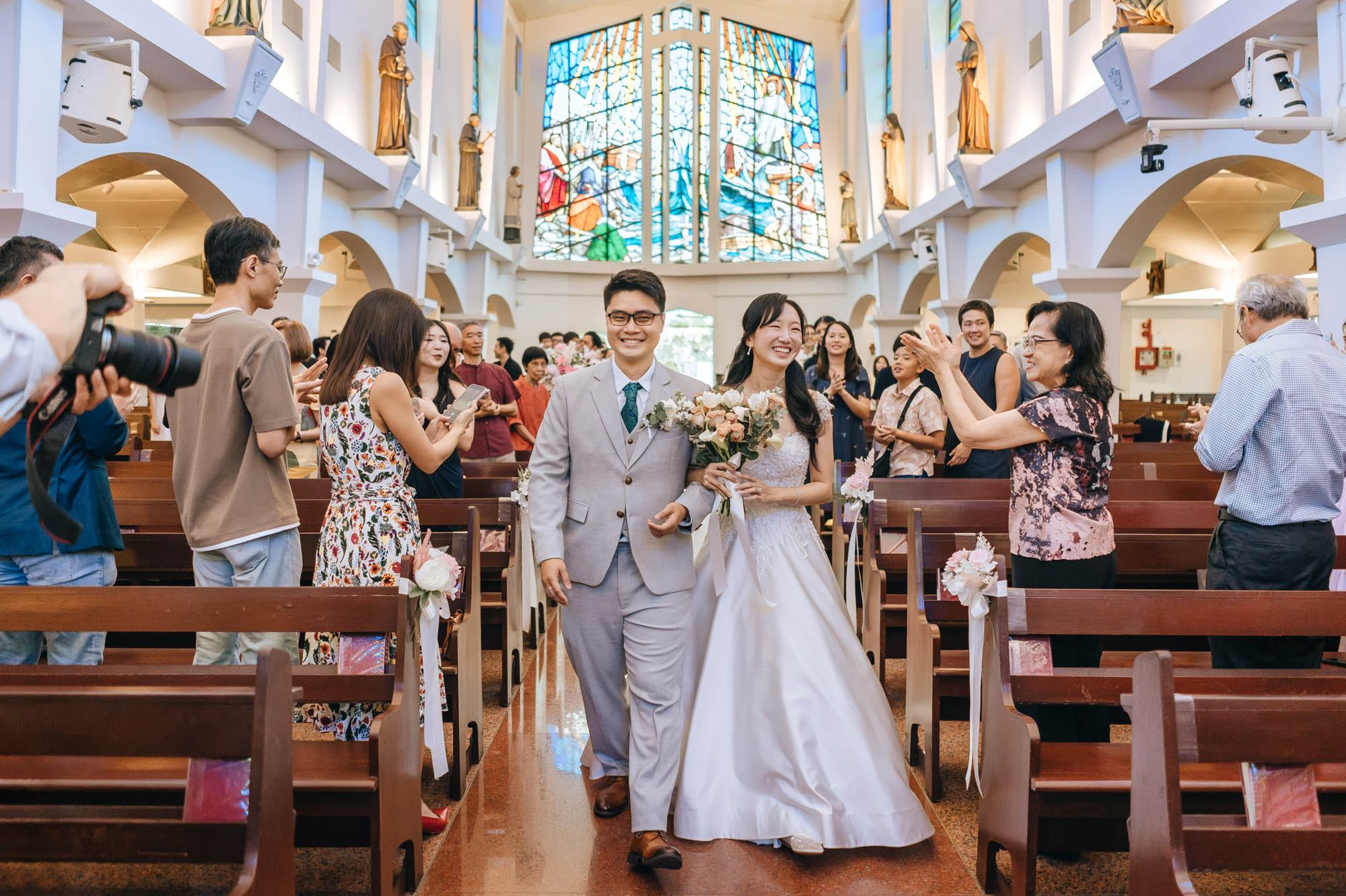beautiful stain glass in the background as the newly weds marches down the aisle